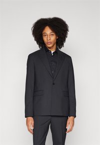 Black blazer with a smooth texture, single button closure, notch lapels, and two front pockets, paired with a matching shirt.