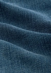 Tummansininen farkkukangas, jossa on sileä pinta ja selkeä vinosauma, joka korostaa pehmeyttä ja hienoista kiiltoa.