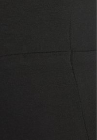 Leggings pretos feitos de um material elástico e canelado. Apresentam costura sem emendas e uma textura suave. A cintura é elástica e ajustada.