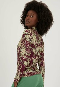 Langarmtop in maroon en groen gemarmerd patroon, met een hoge halslijn en een aansluitend ontwerp, gemaakt van een zachte, rekbare stof.