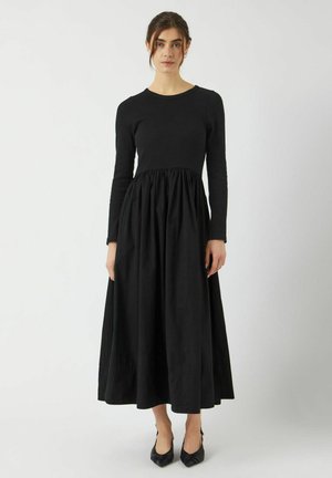 Abito lungo nero con maniche lunghe, un corpetto aderente e una gonna ampia e arricciata. Realizzato in tessuto leggero con una superficie liscia.
