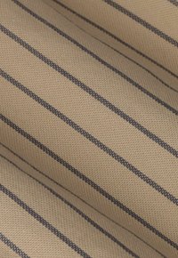 Tissu beige avec des rayures verticales fines, espacées uniformément, de couleur brun foncé, et une texture tissée, présenté avec des plis doux.