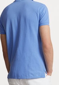 Lichtblauwe polo shirt gemaakt van gestructureerde katoen, met korte mouwen, een traditionele kraag en zijsplitten voor bewegingsgemak.