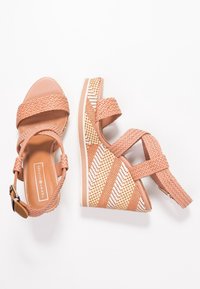 Sandales compensées en tissu rose tressé avec des brides autour de la cheville et des talons compensés tissés rayés, marquées Tommy Hilfiger sur la semelle intérieure.