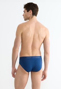 Culotte di cotone blu con texture liscia, cinturino elasticizzato con dettaglio del logo in rilievo e design aderente.