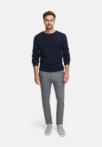 Marineblå ribbestrikket genser kombinert med lysegrå smale bukser og grå joggesko. Antrekket har et teksturert design og en avslappet passform.