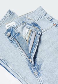 Jean en denim bleu clair avec braguette ouverte et bouton en métal sur la ceinture, montrant le tissu intérieur et les détails de couture.