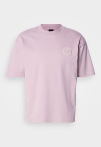 Svetloružové bavlnené tričko s okrúhlym výstrihom, krátkymi rukávmi a malou textúrovanou nášivkou s logom na ľavej strane hrudníka. Hladká textúra.