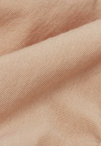 Světle broskvová tkanina s měkkým, texturovaným povrchem. Disponuje jemným žebrovaným pleteným vzorem a hladkým splýváním.