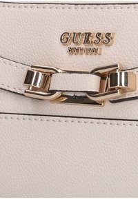 Borsa a tracolla in pelle beige chiaro con chiusura in metallo dorato, marchio impresso e dettagli cuciti lungo i bordi.