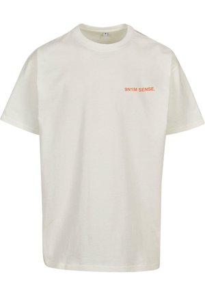Lühikeste varrukatega kreemjas puuvillases T-särgis on vasakus rinnaosas oranž tekst "9N1M SENSE." Klassikaline ümar kaelus.