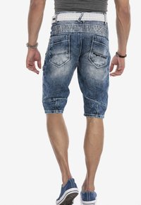 Lichtblauwe denim cargo shorts met whiskering, vijf zakken en een omgeslagen zoom. Versterkt met een witte perforerende riem.