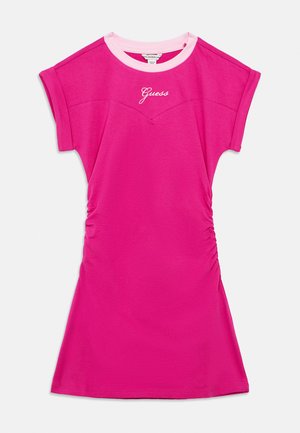 Sterkt rosa kortermet kjole med lys rosa rund hals, rynkede sider, og hvit "Guess"-logo midt på brystet.
