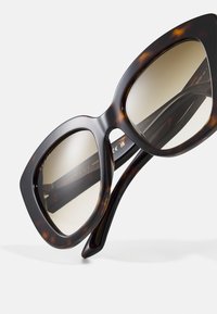 Gafas de sol de gran tamaño con estampado carey y lentes de degradado. Montura de plástico grueso y brillante; logo de la marca visible en el interior. Detalles en la superficie texturizada.