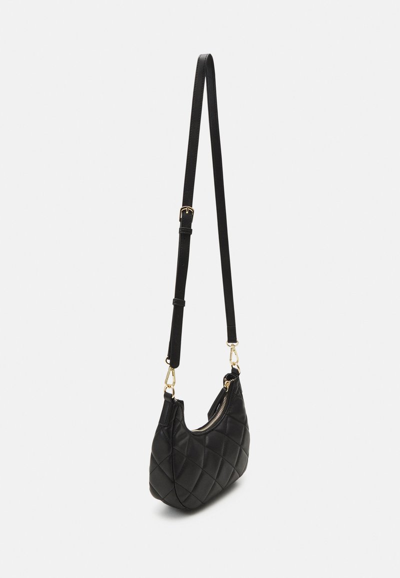 Sac à main noir matelassé de forme courbée, avec une fermeture éclair et une longue bandoulière réglable. Des accents en métal doré ajoutent du détail.