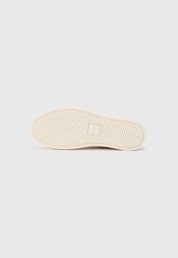 Shoe sole in light beige with horizontal grooves and a square logo embossed with "CLAE" in the center on a plain white background.
