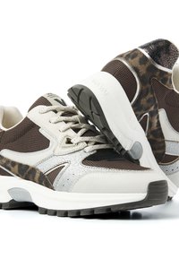 Bruine en crèmekleurige sneakers met een gestructureerde mesh bovenkant, zilveren accenten, luipaardprintdetails en een zwarte rubberen zool.
