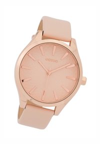 Rose gold watch with a textured dial, minimalist hour markers, and a smooth blush-colored silicone band. Sleek, modern design.