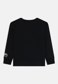 Schwarzes Langarmshirt mit Rundhalsausschnitt, ausgestattet mit einem Logo auf dem linken Ärmel. Hergestellt aus einem weichen, glatten Stoff. Einfaches Design, ohne zusätzliche Details.