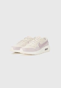Helle beige Sneakers mit lila Akzenten und einem Mesh-Design. Sie verfügen über eine strukturierte Oberfläche und eine sichtbare Luftpolstereinheit in der Ferse.