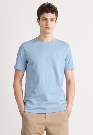 Lys blå bomulds t-shirt med korte ærmer, rund halsudskæring og lille logo detalje på venstre bryst. Blød tekstur, normal pasform.