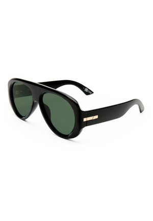 Gafas de sol negras de gran tamaño con lentes verde oscuro y un pequeño detalle decorativo dorado en las patillas, mostradas sobre fondo blanco.