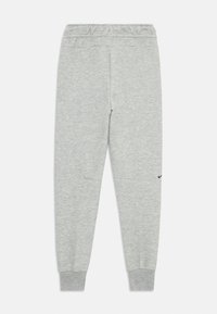 Sive trenirke z elastičnim pasom in manšeta na gležnjih. Imajo majhen črn Nike logotip na levi strani. Material se zdi mehak.