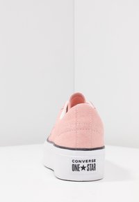 Baskets en daim rose avec une semelle plateforme blanche, logo étoile à l'arrière, et un accent noir le long de la semelle. Présentent des détails cousus et un bout arrondi.