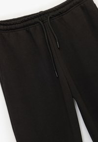 Schwarze Jogginghosen aus weichem Stoff, mit elastischem Bund, Kordelzügen und einem entspannten Schnitt.