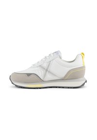 Baskets blanches et grises en matériaux suédés et synthétiques, avec des panneaux en maille, des accents jaunes, une semelle texturée et un design à orteil rond.