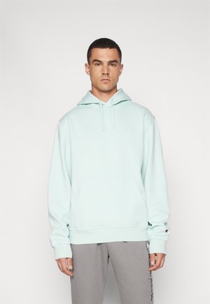 Light blue hoodie with a drawstring hood, kangaroo pocket, ribbed cuffs, and a small logo on the left chest. Paired with gray sweatpants.