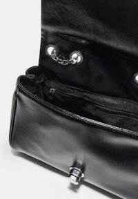 Schwarze Lederhandtasche mit glatter Oberfläche, metallischen Beschlägen, einer Reißverschlussinnentasche und Kettendetails am oberen Verschluss.