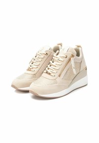 Zapatillas beige con parte superior de ante y malla, acentos de hardware dorado, cierre con cordones, cremalleras laterales y suela de cuña con base blanca.