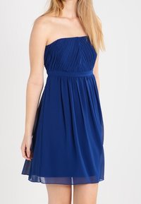 Šaty bez ramínek modré barvy s plisovaným korzetem a přiléhavým pasem, splývavou sukní a jemnou, lehkou tkaninou. Hladký povrch, délka ke kolenům.