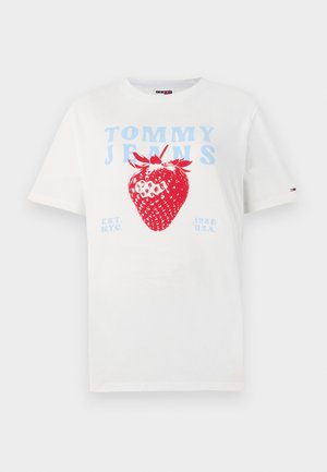White cotton t-shirt featuring a large red strawberry graphic with blue "TOMMY JEANS" text. Simple design, short sleeves, crew neck.