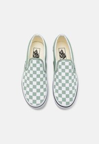 Gröna och vita rutiga slip-on-skor med ett textilt ovandel, en vadderad innersula och en gummiyttersula, med en klassisk Vans-logotyp.