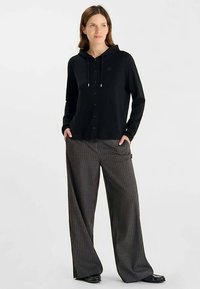 Zwarte cardigan met capuchon met knopen en trekkoorden, gecombineerd met wijde pijpen broek met krijtstrepen. Glad oppervlak, casual ontwerp en comfortabele pasvorm.