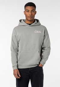Gray hoodie with a front pocket, soft texture, and a printed logo in pink on the left chest. Pull-over design with a spacious hood.