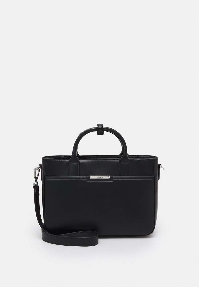 Sac à main rectangulaire en cuir noir avec poignées courtes, bandoulière amovible et plaque de marque métallique à l'avant.