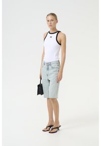 Vit ribbad linne med svarta detaljer, ljusblå denimshorts med fransade kanter, svart handväska och svarta flip-flop sandaler.