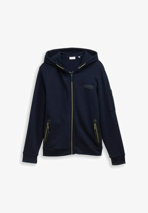 Sweat à zip navy en mélange de coton. Il dispose d'une capuche doublée, de détails de fermeture éclair dorés, de deux poches latérales et d'une patch sur le bras gauche.