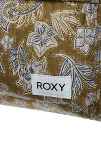 Torebka z pikowanej tkaniny w oliwkowym kolorze z białymi i niebieskimi kwiatowymi wzorami. Posiada białą metkę z napisem "ROXY" grubymi czarnymi literami.