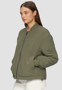 Olijfgroene bomberjack met een ritsluiting, geribde manchetten en zijzakken. Lichtgewicht materiaal met een soepele textuur.