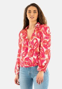 Blusa de manga larga con escote en V profundo, con un patrón de paisley rosa sobre un fondo claro, fabricada en una tela ligera con puños elásticos.