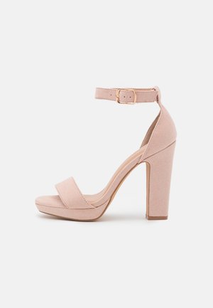 Blush roze platform hak sandaal in zachte suede. Heeft een enkelband met gespsluiting, brede teengedeelte en een stevige blokhak.