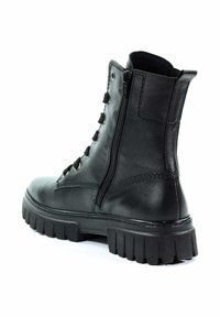 Botines de cuero negro con suela de goma gruesa, cierre de cordones en la parte delantera y cremallera lateral para mayor comodidad al calzarse. Textura suave y diseño minimalista.