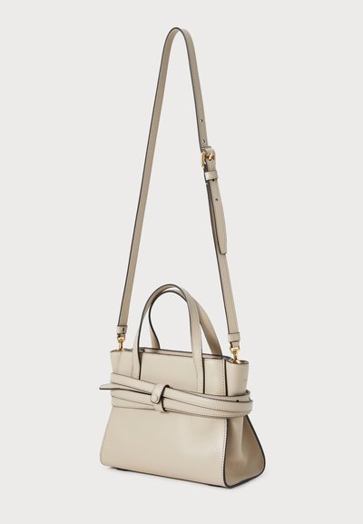 Sac à main en cuir beige avec un design structuré, des poignées supérieures, une bandoulière réglable et un détail de fermeture distinctif en forme de ruban.
