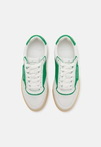 Baskets blanches avec des accents verts, en cuir et caoutchouc, embout perforé et lacets plats. Semelle extérieure en caoutchouc texturé.