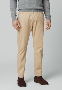 Beige bomulds-chinos med lige ben, der har sidelommer og en glat tekstur, parret med brune swede ankelstøvler.