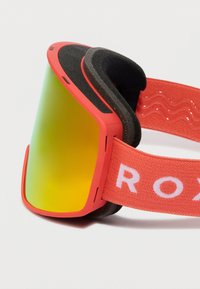 Červené snehové okuliare s žltými reflexnými šošovkami a čiernou penovou výplňou, pripevnené na červenom nastaviteľnom páse s bielym textom.